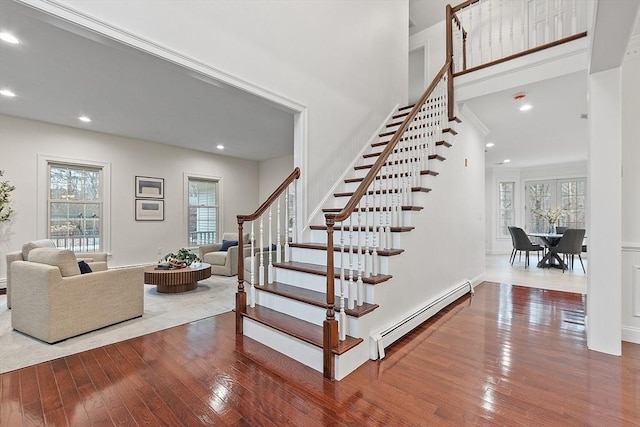 stairway with baseboard heating, a healthy amount of sunlight, and hardwood / wood-style flooring