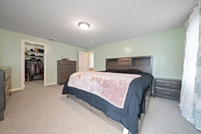 bedroom featuring a walk in closet, light colored carpet, and a closet