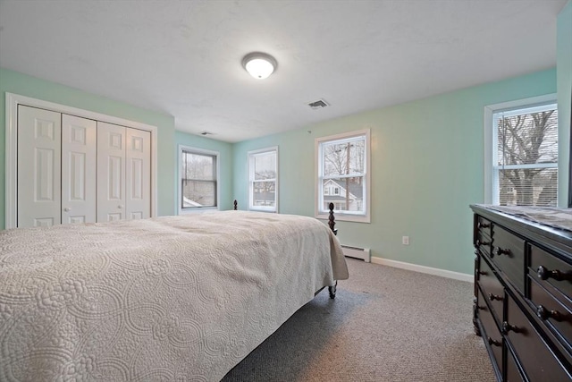 bedroom featuring light carpet, a baseboard heating unit, and a closet