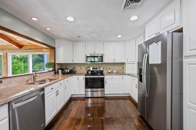 146 Field St, Taunton, MA 02780 - kitchen with stainless steel appliances, dark wood finished floors, light stone countertops, white cabinets, and backsplash