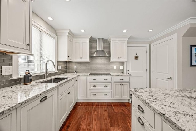 kitchen with dark wood finished floors, black electric cooktop, wall chimney range hood, white cabinetry, and a sink