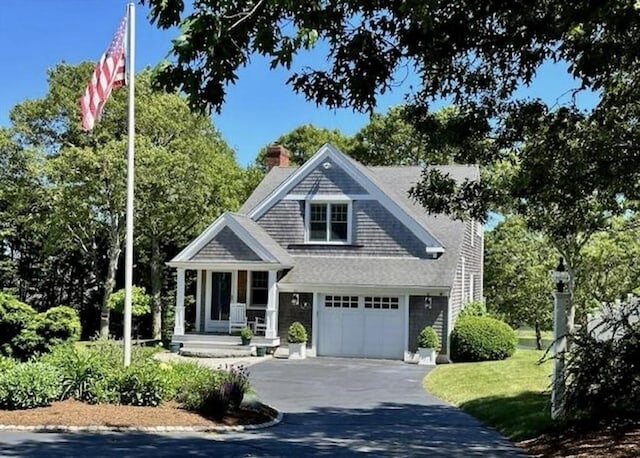 shingle-style home featuring aphalt driveway, a front yard, a chimney, and an attached garage