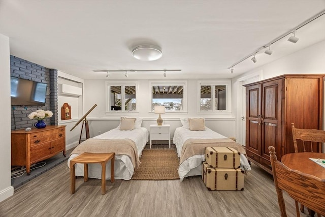 bedroom featuring a wall unit AC, light wood-style flooring, and track lighting