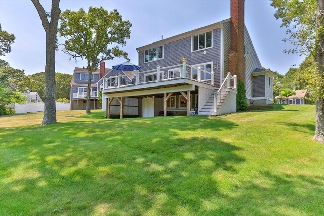 back of house with a yard, a chimney, a wooden deck, and stairs