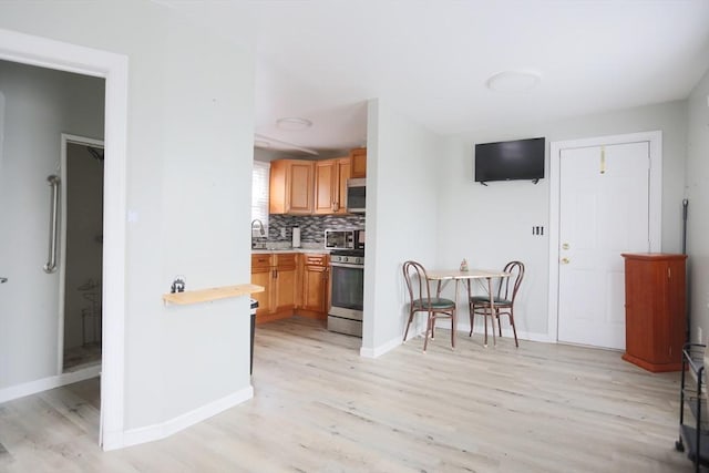 kitchen with tasteful backsplash, sink, light hardwood / wood-style floors, and appliances with stainless steel finishes