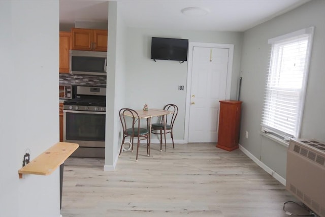 dining space with radiator heating unit and light wood-type flooring