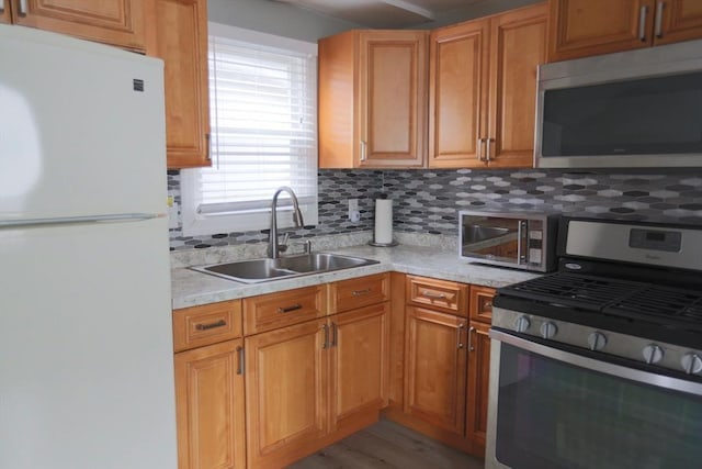 kitchen featuring light stone countertops, sink, light hardwood / wood-style floors, decorative backsplash, and appliances with stainless steel finishes