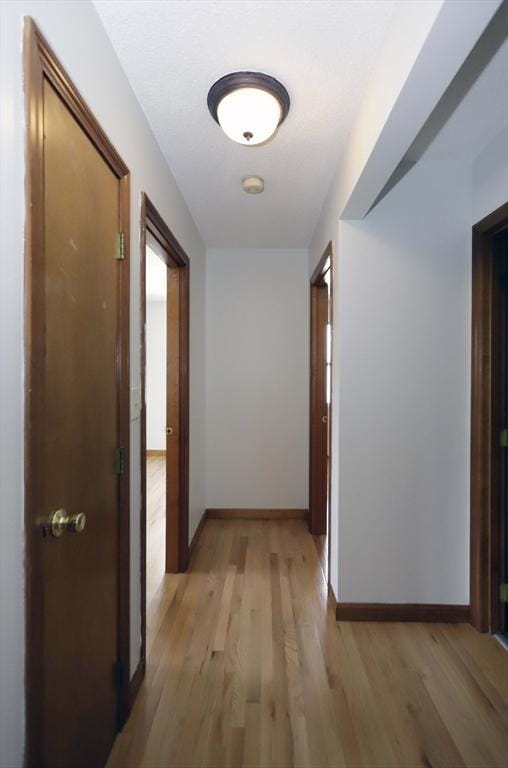 hallway with light wood-style flooring and baseboards