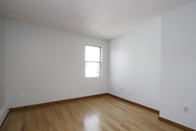 unfurnished room featuring light wood-style floors, a baseboard radiator, and baseboards