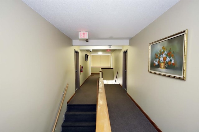 corridor with carpet floors, baseboards, and an upstairs landing