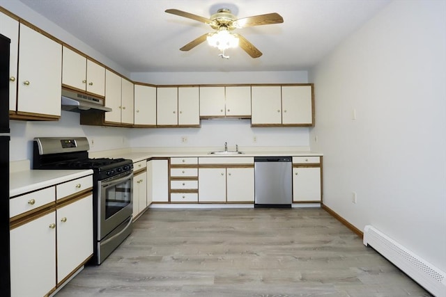 kitchen with a baseboard radiator, under cabinet range hood, white cabinets, light countertops, and appliances with stainless steel finishes