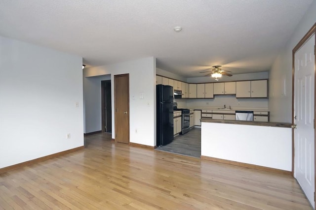 kitchen featuring cream cabinets, stainless steel dishwasher, stove, freestanding refrigerator, and open floor plan