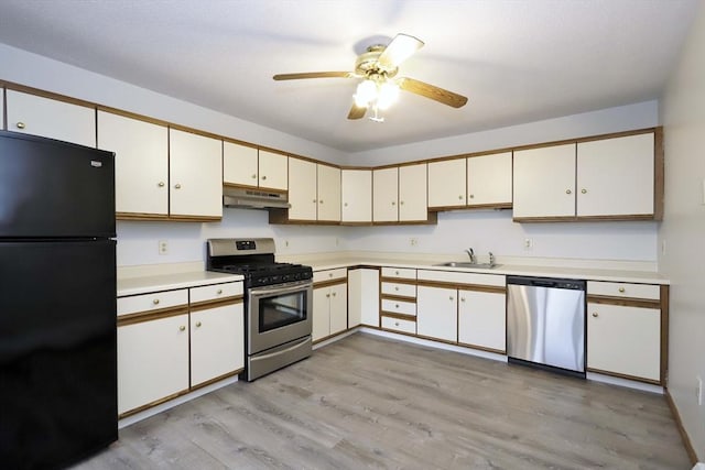 kitchen featuring appliances with stainless steel finishes, light countertops, under cabinet range hood, white cabinetry, and a sink