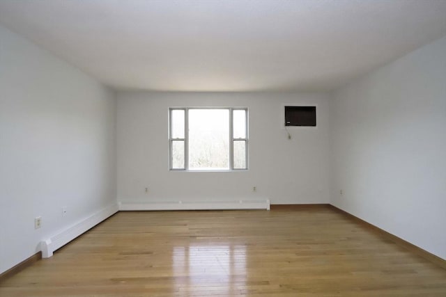 unfurnished room with a baseboard radiator, light wood-style flooring, and baseboards