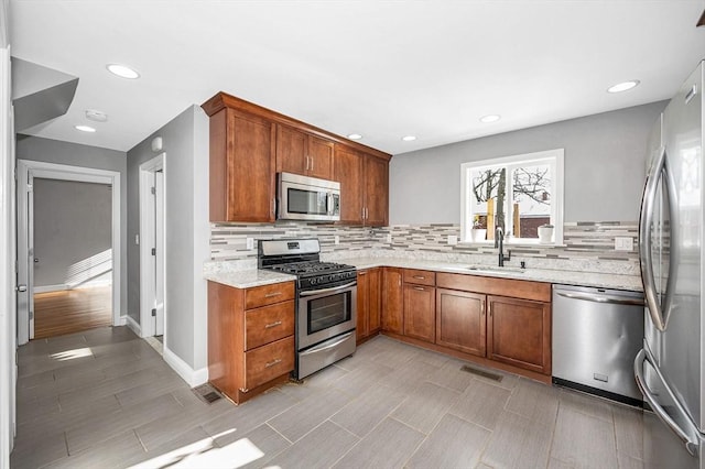 kitchen featuring tasteful backsplash, appliances with stainless steel finishes, sink, and light stone counters