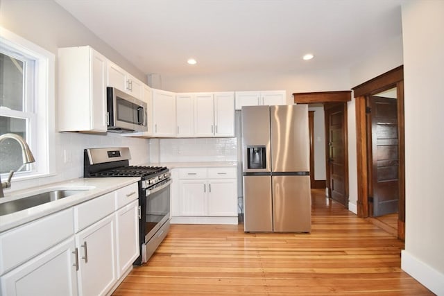 130 Center St, Ludlow, MA 01056 - kitchen featuring stainless steel appliances, a sink, light countertops, decorative backsplash, and white cabinetry