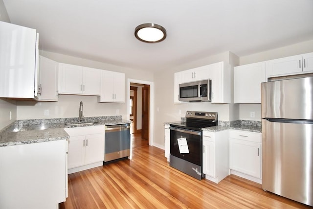 130 Center St, Ludlow, MA 01056 - kitchen with appliances with stainless steel finishes, a sink, light wood finished floors, white cabinetry, and light stone countertops