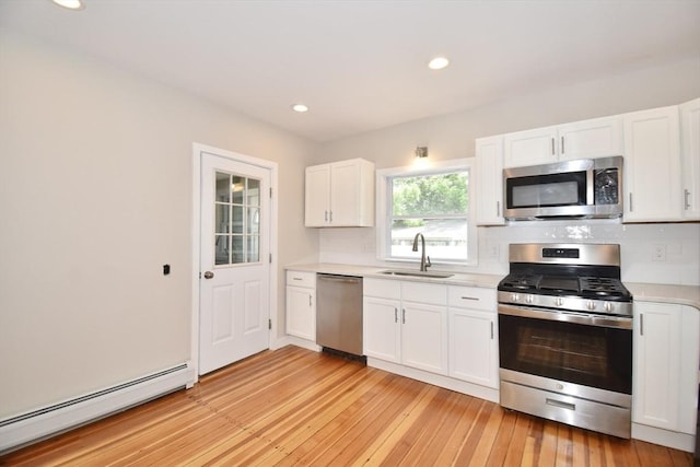 130 Center St, Ludlow, MA 01056 - kitchen featuring appliances with stainless steel finishes, a sink, a baseboard radiator, light countertops, and decorative backsplash