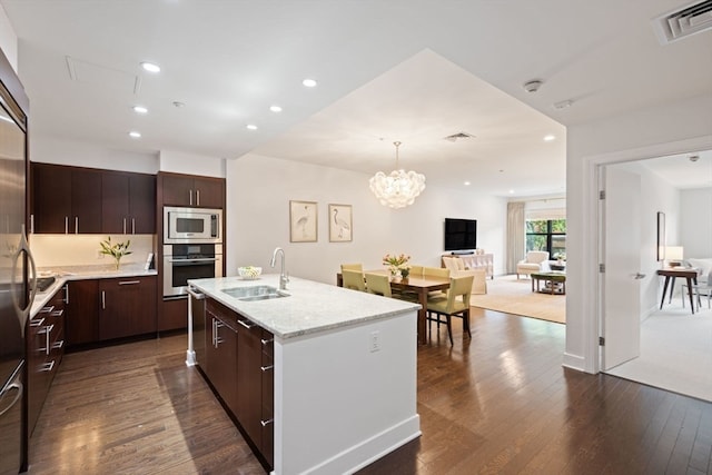 kitchen featuring dark hardwood / wood-style floors, an island with sink, stainless steel appliances, sink, and dark brown cabinetry