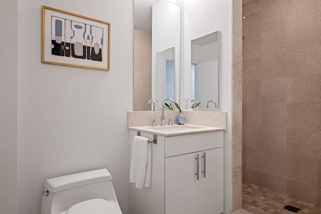 bathroom featuring toilet, vanity, and a tile shower