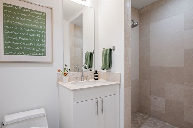 bathroom with vanity, toilet, and a tile shower