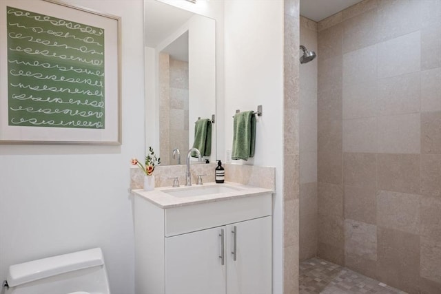 bathroom with vanity, backsplash, toilet, and tiled shower