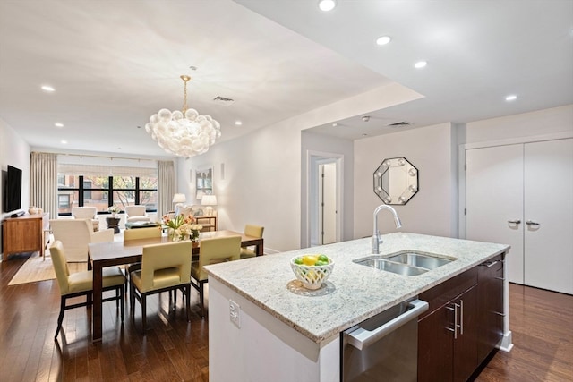 kitchen featuring dishwasher, dark hardwood / wood-style floors, a center island with sink, sink, and an inviting chandelier