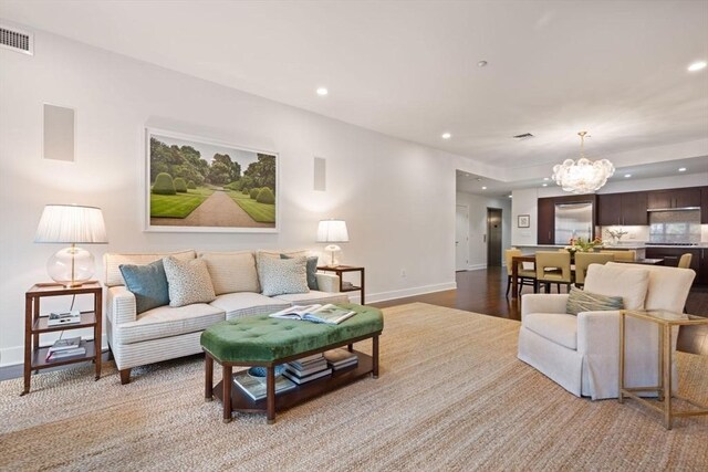 living room featuring an inviting chandelier, baseboards, recessed lighting, and visible vents