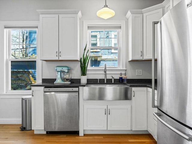 kitchen with light wood finished floors, white cabinets, appliances with stainless steel finishes, and a sink