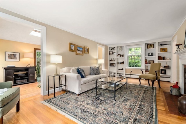19 Birch St, Millis, MA 02054 - living room featuring built in features, light wood finished floors, ornamental molding, a fireplace, and a baseboard radiator