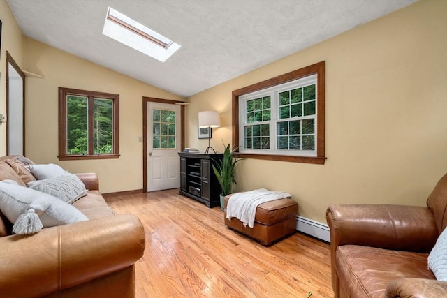 19 Birch St, Millis, MA 02054 - living area featuring a baseboard radiator, lofted ceiling, a skylight, plenty of natural light, and light wood-style floors