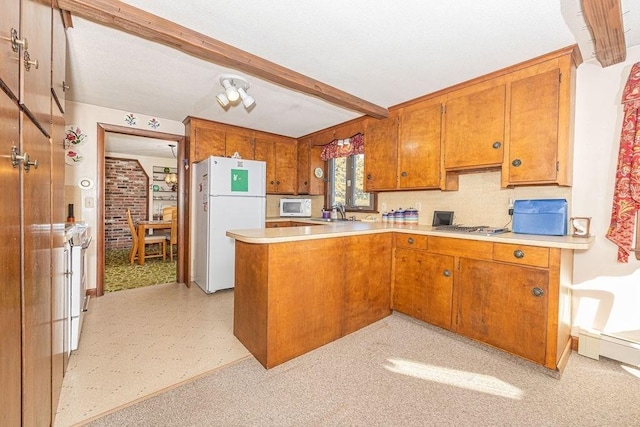 kitchen with kitchen peninsula, sink, beamed ceiling, and white appliances