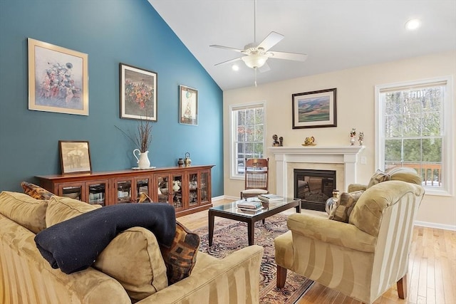 living room featuring lofted ceiling, light wood-style floors, a glass covered fireplace, and a healthy amount of sunlight