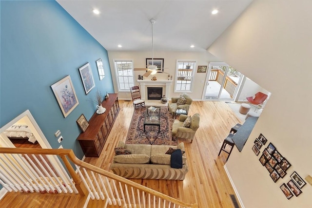 living area with a glass covered fireplace, stairway, and wood finished floors