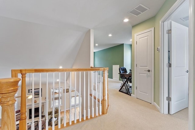 hallway with an upstairs landing, recessed lighting, visible vents, and light colored carpet