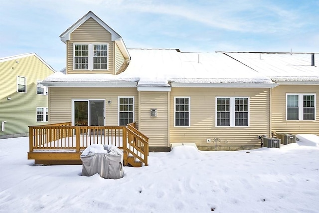 snow covered back of property with central AC and a wooden deck