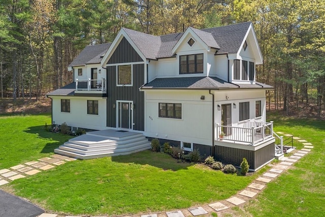 view of front of house with a shingled roof, a front lawn, and a balcony