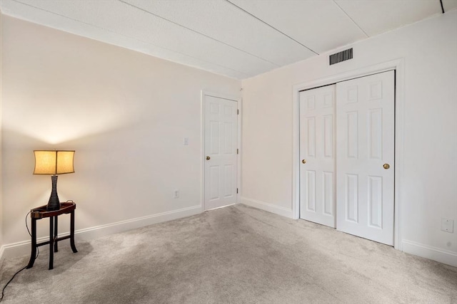 unfurnished bedroom with light carpet and a closet