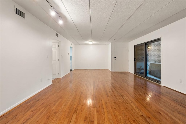 spare room with a textured ceiling and hardwood / wood-style flooring