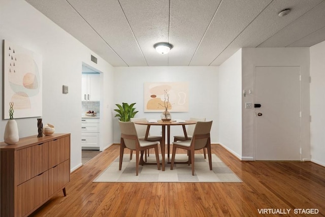 dining room with a textured ceiling and hardwood / wood-style flooring