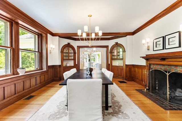 10 Eliot Rd, Lexington, MA 02421 - dining room featuring a wainscoted wall, light wood finished floors, a chandelier, a fireplace, and crown molding