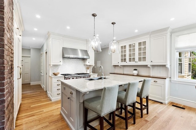 10 Eliot Rd, Lexington, MA 02421 - kitchen featuring ventilation hood, ornamental molding, tasteful backsplash, light wood-type flooring, and an island with sink
