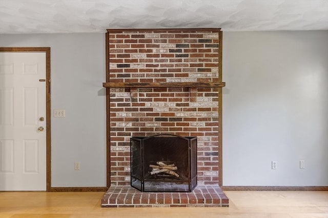 146 Lowell Rd, Pepperell, MA 01463 - detailed view of a brick fireplace, wood finished floors, and a textured ceiling