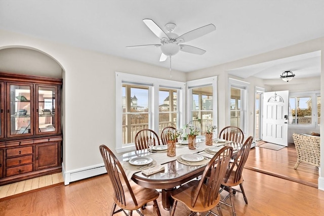 dining space featuring baseboards, light wood-style flooring, a baseboard heating unit, and a ceiling fan