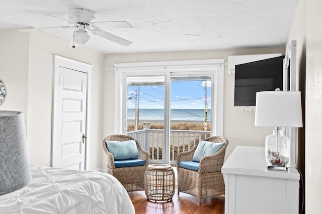 bedroom with a water view, ceiling fan, a textured ceiling, and wood finished floors