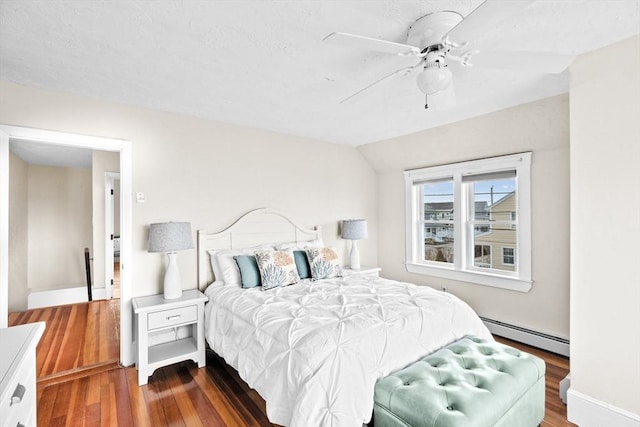 bedroom with lofted ceiling, ceiling fan, baseboard heating, and wood finished floors