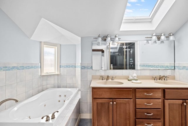 bathroom featuring a skylight, a sink, a jetted tub, and double vanity