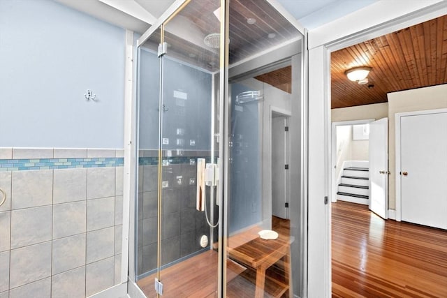 bathroom featuring tile walls, wooden ceiling, a shower stall, and wood finished floors