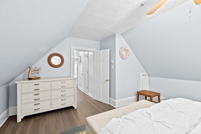 bedroom featuring dark wood-style floors, baseboards, vaulted ceiling, and a ceiling fan