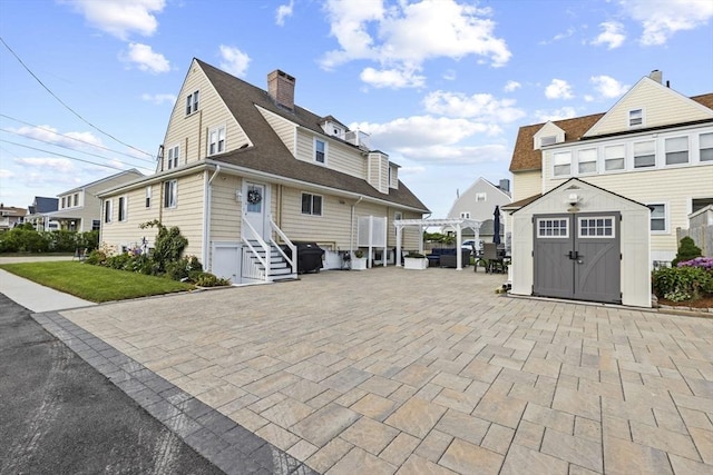 exterior space featuring entry steps, a patio, a storage unit, an outdoor structure, and a pergola